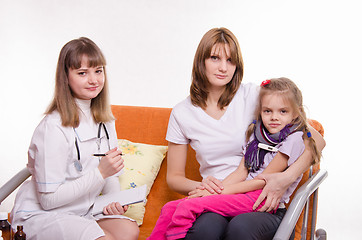 Image showing Sick girl measures the temperature of sitting on lap mother and doctor writes a complaint