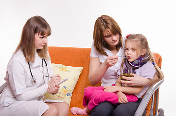 Image showing Pediatrician prescribes treatment child whose mother gives to drink tea from a spoon