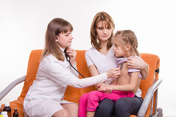 Image showing Pediatrician checks breath stethoscope a little girl in the arms of mother
