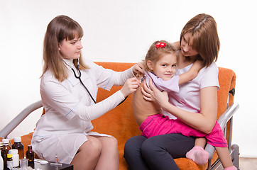 Image showing Doctor listening stethoscope back at girl sitting in hands of mother