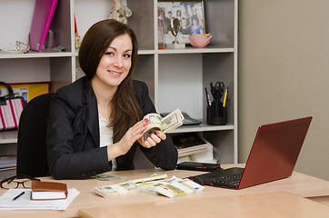 Image showing Girl in office happily turns the money a pack