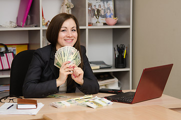 Image showing girl behind desk office in front him holding a fan of money