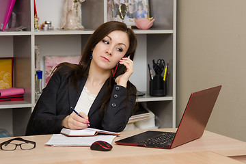 Image showing girl at desk prepared to write in a notebook information obtained from telephone conversation