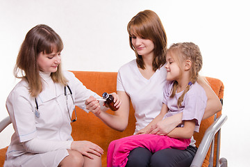 Image showing Pediatrician pours medicine into a spoon, which holds mother of sick child