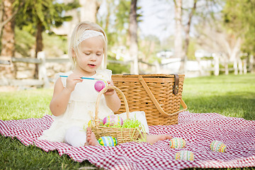 Image showing Cute Baby Girl Coloring Easter Eggs on Picnic Blanket