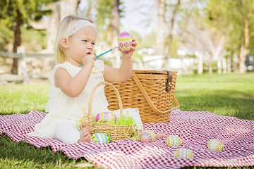 Image showing Cute Baby Girl Coloring Easter Eggs on Picnic Blanket
