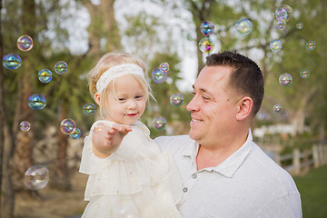 Image showing Father Holding Baby Girl Enjoying Bubbles Outside at Park