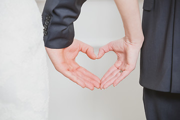 Image showing wedding couple showing shape of heart from their hands.