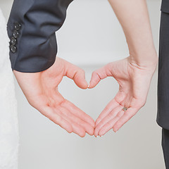 Image showing wedding couple showing shape of heart from their hands.