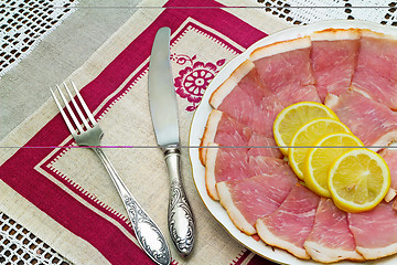 Image showing The dish with slices of ham and lemon 