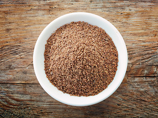 Image showing Bowl of crushed flax seeds on old wooden table