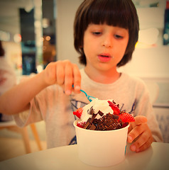 Image showing boy eating ice cream with chocolate and strawberries