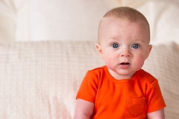 Image showing Young Blue Eyed Infant Boy Sitting up Looking at Camera