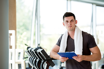 Image showing trainer with clipboard standing in a bright gym