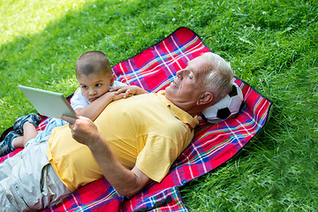 Image showing grandfather and child in park using tablet