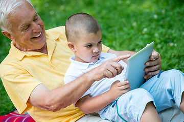 Image showing grandfather and child in park using tablet