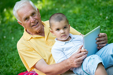 Image showing grandfather and child in park using tablet