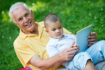 Image showing grandfather and child in park using tablet