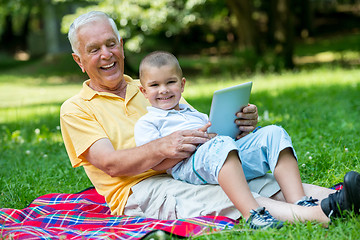 Image showing grandfather and child in park using tablet