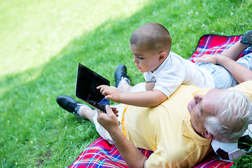 Image showing grandfather and child in park using tablet