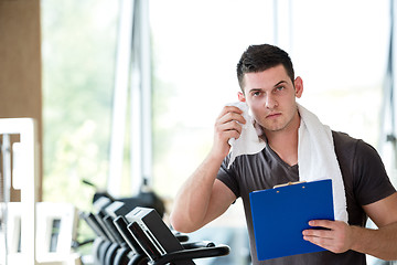 Image showing trainer with clipboard standing in a bright gym