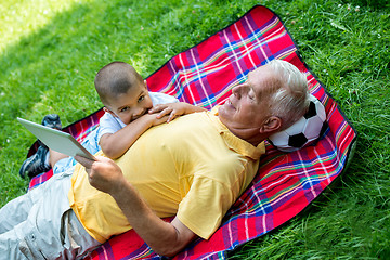 Image showing grandfather and child in park using tablet