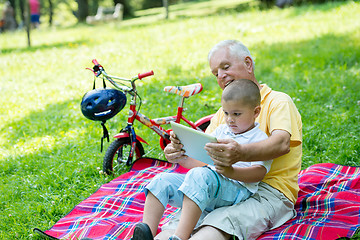 Image showing grandfather and child in park using tablet