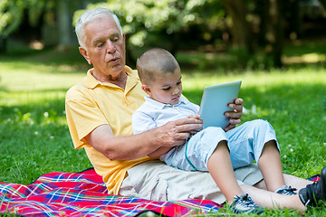 Image showing grandfather and child in park using tablet