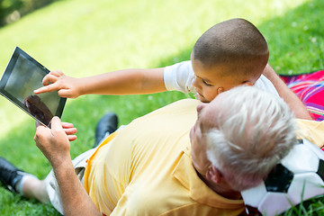 Image showing grandfather and child in park using tablet