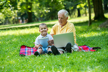 Image showing grandfather and child in park using tablet