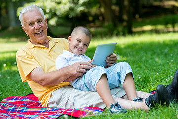 Image showing grandfather and child in park using tablet