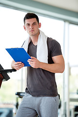 Image showing trainer with clipboard standing in a bright gym