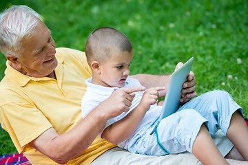 Image showing grandfather and child in park using tablet