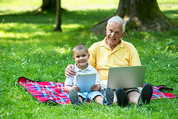 Image showing grandfather and child in park using tablet