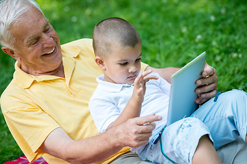 Image showing grandfather and child in park using tablet