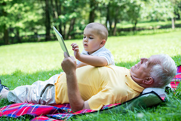 Image showing grandfather and child in park using tablet