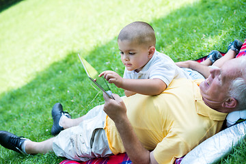 Image showing grandfather and child in park using tablet