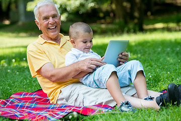 Image showing grandfather and child in park using tablet