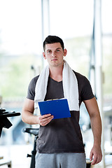 Image showing trainer with clipboard standing in a bright gym