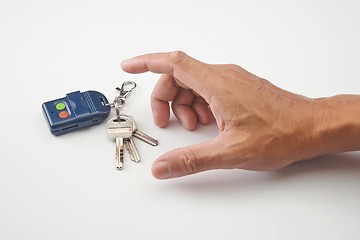 Image showing A hand want to get remote control and keys