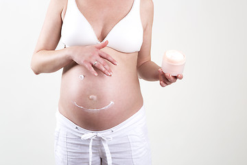 Image showing Pregnant woman putting smiley with creme on her belly