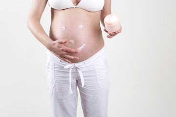 Image showing Pregnant woman putting smiley with creme on her belly
