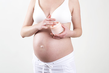 Image showing Pregnant woman putting creme on her belly