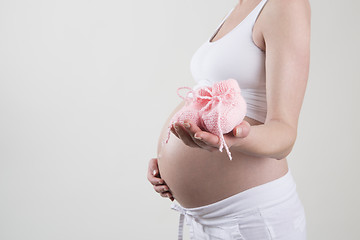 Image showing Pregnant woman holding pink baby shoes in her hands