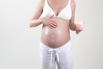 Image showing Pregnant woman putting creme on her belly