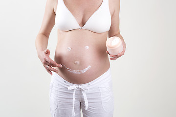 Image showing Pregnant woman putting smiley with creme on her belly