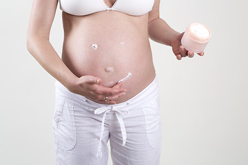 Image showing Pregnant woman putting smiley with creme on her belly