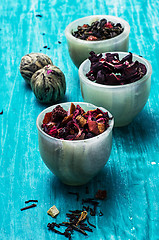 Image showing variety of dry tea leaves in jade stacks on wooden background