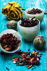 Image showing variety of dry tea leaves in jade stacks on wooden background