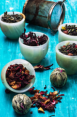 Image showing variety of dry tea leaves in jade stacks on wooden background